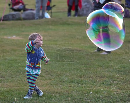 Téléchargez les photos : Un homme et son fils admirent les bulles lors de la célébration du solstice d'été du Cercle de pierre de Castlerigg, Royaume-Uni, 20 juin 2023 - en image libre de droit