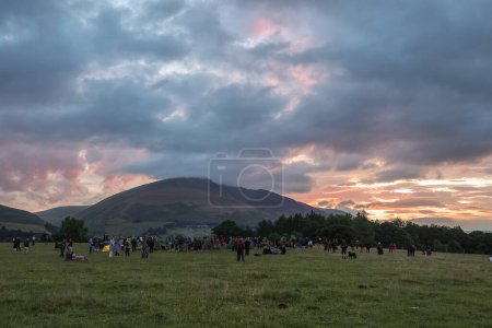 Téléchargez les photos : Les gens se rassemblent pour regarder le soleil se lever pendant la célébration du solstice d'été du Cercle de pierre de Castlerigg, Royaume-Uni, 20 juin 2023 - en image libre de droit