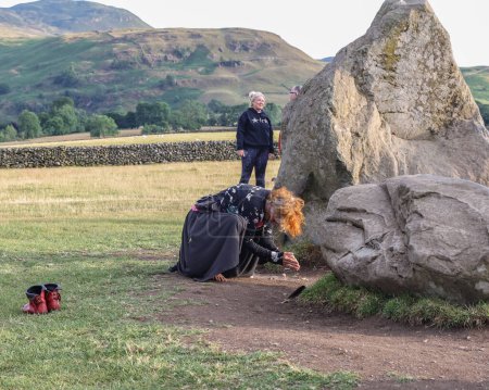Téléchargez les photos : Une personne exécute une danse devant les pierres alors que le soleil commence à se coucher pendant le cercle de pierre de Castlerigg. Célébration du solstice d'été, Royaume-Uni, 20 juin 2023 - en image libre de droit