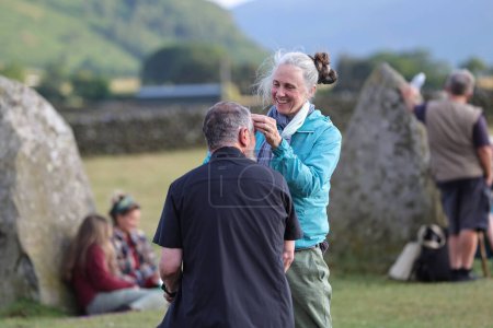 Photo for A person has their hair cut by their partner during the Castlerigg Stone Circle Summer Solstice Celebration, United Kingdom, 20th June 2023 - Royalty Free Image