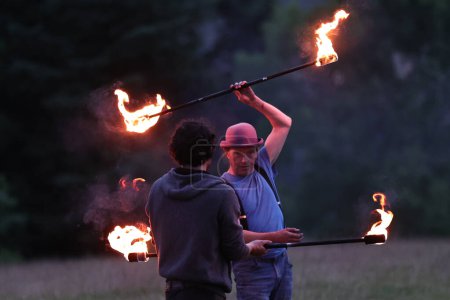 Téléchargez les photos : Un participant fait tournoyer un bâton de feu pendant qu'il divertit les spectateurs pendant le Cercle de pierre de Castlerigg. Célébration du solstice d'été, Royaume-Uni, 20 juin 2023 - en image libre de droit