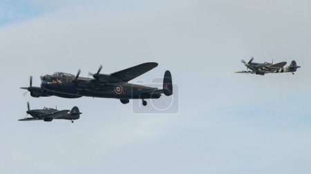 Photo for The Battle of Britain Memorial Flight of Hawker Hurricane PZ865 (right), Lancaster bomber PA474 (centre) and Mk Vb Spitfire, AB910 (left) run into the show to perform their display, during Rhyl Air Show 2023 at Rhyl Seafront, Rhyl, United Kingdom - Royalty Free Image