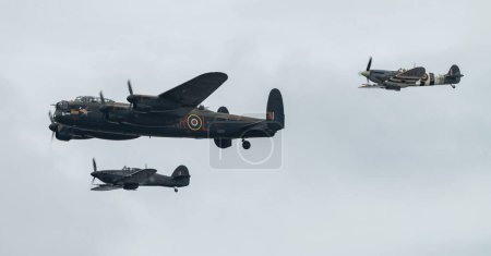 Téléchargez les photos : Le Battle of Britain Memorial Flight of Hawker Hurricane PZ865 (à droite), le bombardier Lancaster PA474 (au centre) et le Mk Vb Spitfire, AB910 (à gauche) se précipitent dans le spectacle pour présenter leur spectacle, lors du Rhyl Air Show 2023 au Rhyl Seafront, Rhyl, Royaume-Uni - en image libre de droit