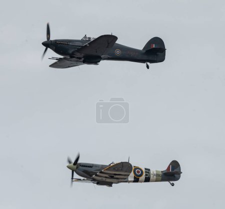 Photo for The Battle of Britain Memorial Flights of Hawker Hurricane PZ865 (above) and Mk Vb Spitfire, AB910 (below) fly pass, during Rhyl Air Show 2023 at Rhyl Seafront, Rhyl, United Kingdom, 27th August 2023 - Royalty Free Image