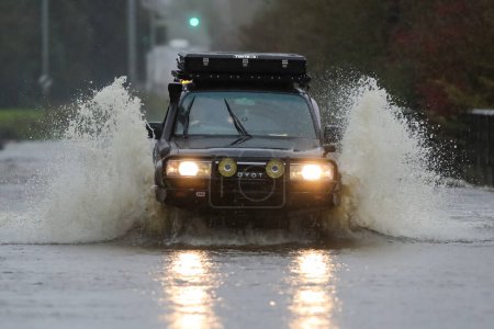 Foto de Un vehículo 4x4 se enfrenta a una carretera inundada en Allerton Bywater, Leeds, después de que el río Aire estallara sus orillas mientras la tormenta Babet golpea el Reino Unido en Allerton Bywater, Allerton Bywater, Reino Unido, 20 de octubre 202 - Imagen libre de derechos