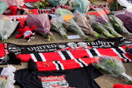 Téléchargez les photos : Foulards et fleurs posés en hommage au regretté Sir Bobby Charlton devant Old Trafford, Manchester, Royaume-Uni, 23 octobre 2023 - en image libre de droit