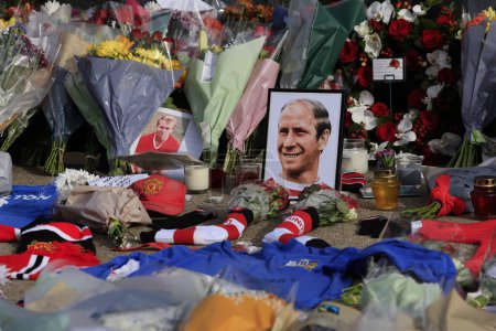 Téléchargez les photos : Fleurs et photographies en hommage au regretté Sir Bobby Charlton devant Old Trafford, Manchester, Royaume-Uni, 23 octobre 2023 - en image libre de droit