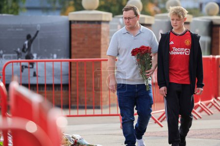 Photo for Father and son bring some flowers in tribute to the late Sir Bobby Charlton outside of Old Trafford, Manchester, United Kingdom, 23rd October 2023 - Royalty Free Image