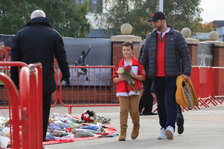 Téléchargez les photos : Un jeune fan et son père apportent des fleurs en hommage au regretté Sir Bobby Charlton devant Old Trafford, Manchester, Royaume-Uni, 23 octobre 2023 - en image libre de droit