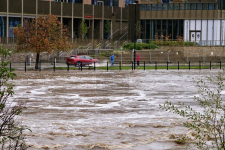 Téléchargez les photos : Une voiture éclabousse les piétons alors que la rivière Wear éclate ses berges et crue à River Wear, Durham, Royaume-Uni, 29 octobre 2023 - en image libre de droit