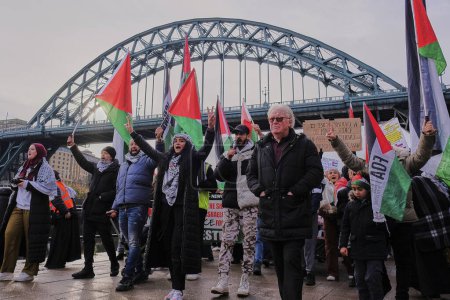 Photo for A protestors holding the Palestinian flag march during the Palestinian March at Newcastle Quayside at Newcastle Quayside, Newcastle Upon Tyne, United Kingdom, 18th November 2023 - Royalty Free Image
