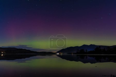 Northern Lights también se conoce como la aurora boreal brilla sobre el agua Derwent y Skiddaw, Keswick, Reino Unido, 1 de diciembre de 2023