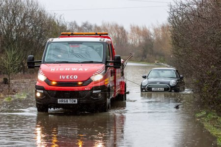 Téléchargez les photos : Une camionnette de récupération tire une voiture coincée sur la route inondée causée par des tempêtes et de fortes pluies près de Leeds sur Newton Lane, Fairburn, Castleford, Royaume-Uni, 2 janvier 2023 - en image libre de droit