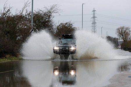 Téléchargez les photos : Une voiture traverse la route inondée causée par les tempêtes et les fortes pluies sur l'A656 près de Leeds à Barnsdale Road A656, Allerton Bywater, Castleford, Royaume-Uni, 2 janvier 2023 - en image libre de droit