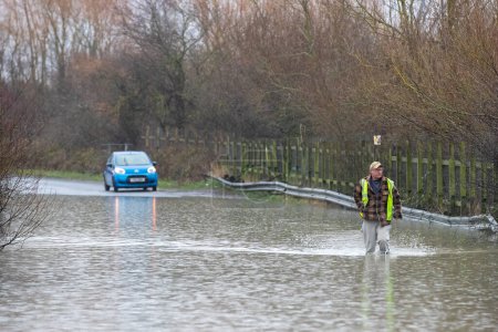 Téléchargez les photos : Un homme marche à travers la route inondée causée par des tempêtes et de fortes pluies près de Leeds sur Newton Lane, Fairburn, Castleford, Royaume-Uni, 2 janvier 2023 - en image libre de droit