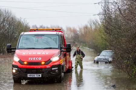 Foto de Una furgoneta de recuperación de carreteras tira de un coche atascado en la carretera inundada causada por tormentas y fuertes lluvias cerca de Leeds en Newton Lane, Fairburn, Castleford, Reino Unido, 2 de enero de 2023 - Imagen libre de derechos