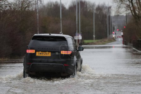 Téléchargez les photos : Une voiture traverse la route inondée causée par les tempêtes et les fortes pluies sur l'A656 près de Leeds à Barnsdale Road A656, Allerton Bywater, Castleford, Royaume-Uni, 2 janvier 2023 - en image libre de droit