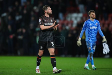 Photo for Matthew Pennington of Blackpool applauds the travelling fans after the Sky Bet League 1 match Cheltenham Town vs Blackpool at The Completely-Suzuki Stadium, Cheltenham, United Kingdom, 13th February 202 - Royalty Free Image