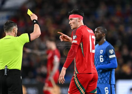 Photo for Referee Istvn Kovcs yellow cards Kieffer Moore of Wales, during the UEFA Euro Qualifiers Play-Off Semi-Final match Wales vs Finland at Cardiff City Stadium, Cardiff, United Kingdom, 21st March 2024 - Royalty Free Image