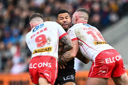 Photo for Kruise Leeming of Wigan Warriors is tackled by Daryl Clark of St. Helens and Curtis Sironen of St. Helens during the Betfred Super League Round 6 match St Helens vs Wigan Warriors at Totally Wicked Stadium, St Helens, United Kingdom, 29th March 202 - Royalty Free Image
