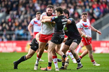 Photo for Alex Walmsley of St. Helens is tackled by Jai Field of Wigan Warriors and Liam Byrne of Wigan Warriors during the Betfred Super League Round 6 match St Helens vs Wigan Warriors at Totally Wicked Stadium, St Helens, United Kingdom, 29th March 202 - Royalty Free Image