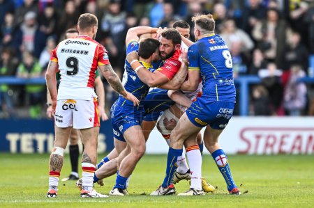 Photo for Julian Bousquet of Catalan Dragons is tackled by Danny Walker of Warrington Wolves and James Harrison of Warrington Wolves during the Betfred Super League match Warrington Wolves vs Catalans Dragons at Halliwell Jones Stadium, Warrington, United King - Royalty Free Image