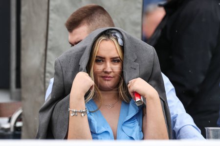 Photo for A racergoer takes cover as it begins to rain during the Randox Grand National 2024 Opening Day at Aintree Racecourse, Liverpool, United Kingdom, 11th April 202 - Royalty Free Image