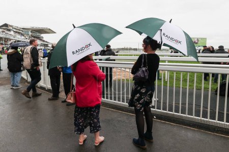 Foto de Racegoers refugio de la lluvia bajo paraguas durante el Randox Grand National 2024 Opening Day en Aintree Racecourse, Liverpool, Reino Unido, 11 de abril 202 - Imagen libre de derechos