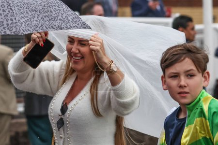 Téléchargez les photos : Un coureur se met à l'abri alors qu'il commence à pleuvoir lors de la journée d'ouverture du Randox Grand National 2024 à l'hippodrome d'Aintree, Liverpool, Royaume-Uni, 11 avril 202 - en image libre de droit