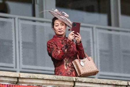 Photo for A Racegoer takes a photo during the The Randox Grand National 2024 Ladies Day at Aintree Racecourse, Liverpool, United Kingdom, 12th April 202 - Royalty Free Image