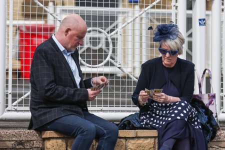 Téléchargez les photos : Coureurs jouant aux cartes lors de la Journée nationale des dames du Randox 2024 à l'hippodrome d'Aintree, Liverpool, Royaume-Uni, 12 avril 202 - en image libre de droit
