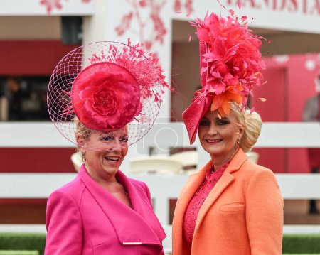 Photo for Two ladies arrive wearing pink and orange dresses and hats during the Randox Grand National Day 2024 at Aintree Racecourse, Liverpool, United Kingdom, 13th April 202 - Royalty Free Image