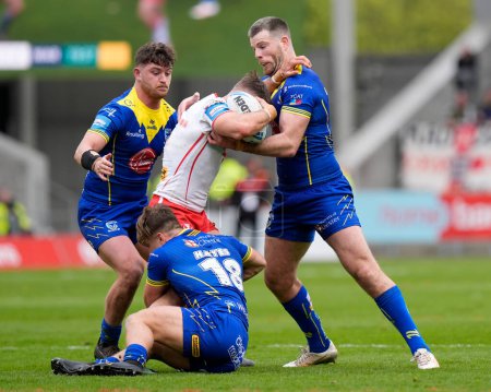Photo for Jordy Crowther of Warrington Wolves and Lachlan Fitzgibbon of Warrington Wolves combine to tackle Tommy Makinson of St. Helens during the Betfred Challenge Cup Quarter Final match St Helens vs Warrington Wolves at Totally Wicked Stadium, St Helens, U - Royalty Free Image