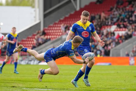 Photo for Matt Dufty of Warrington Wolves offloads the ball to George Williams of Warrington Wolves who went on to score a try during the Betfred Challenge Cup Quarter Final match St Helens vs Warrington Wolves at Totally Wicked Stadium, St Helens, United King - Royalty Free Image