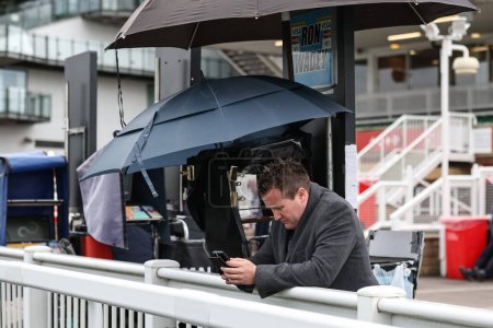 Photo for A bookmakers check his phone ahead of punters arriving during the Randox Grand National Day 2024 at Aintree Racecourse, Liverpool, United Kingdom, 13th April 202 - Royalty Free Image