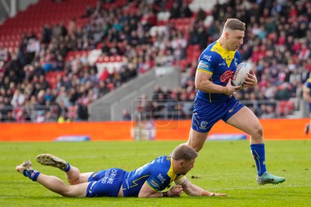 Photo for Matt Dufty of Warrington Wolves offloads the ball to George Williams of Warrington Wolves who went on to score a try during the Betfred Challenge Cup Quarter Final match St Helens vs Warrington Wolves at Totally Wicked Stadium, St Helens, United King - Royalty Free Image