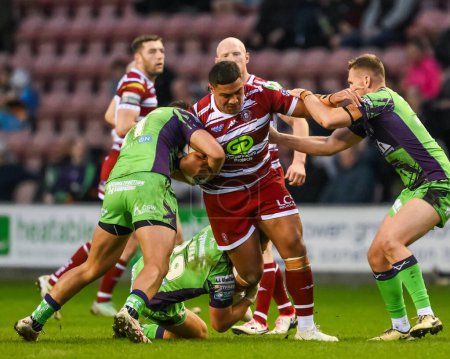 Photo for Patrick Mago of Wigan Warriors is tackled by Elie El-Zakhem of Castleford Tigers during the Betfred Super League Round 8 match Wigan Warriors vs Castleford Tigers at DW Stadium, Wigan, United Kingdom, 19th April 202 - Royalty Free Image