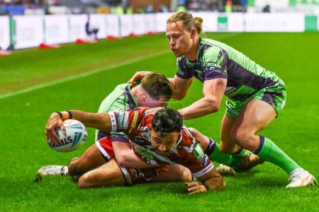 Photo for Bevan French of Wigan Warriors is tackled by Jack Broadbent of Castleford Tigers as he reaches for the try line during the Betfred Super League Round 8 match Wigan Warriors vs Castleford Tigers at DW Stadium, Wigan, United Kingdom, 19th April 202 - Royalty Free Image