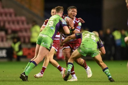 Photo for Patrick Mago of Wigan Warriors is tackled by Sam Hall of Castleford Tigers and George Hill of Castleford Tigers during the Betfred Super League Round 8 match Wigan Warriors vs Castleford Tigers at DW Stadium, Wigan, United Kingdom, 19th April 202 - Royalty Free Image