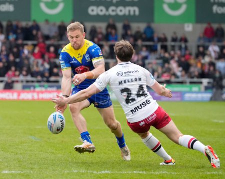 Photo for Matt Dufty of Warrington Wolves chips the ball past Joe Mellor of Salford Red Devils during the Betfred Super League Round 9 match Salford Red Devils vs Warrington Wolves at Salford Community Stadium, Eccles, United Kingdom, 27th April 202 - Royalty Free Image