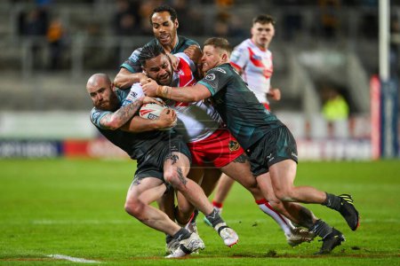 Photo for Konrad Hurrell of St. Helens is tackled by Luke Yates, Leroy Cudjoe and Jake Bibby of Huddersfield Giants during the Betfred Super League Round 9 match St Helens vs Huddersfield Giants at Totally Wicked Stadium, St Helens, United Kingdom, 25th April - Royalty Free Image