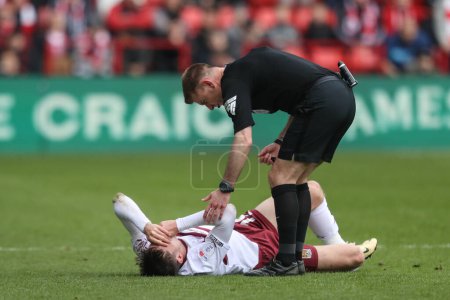 Photo for Referee Ollie Yates checks on Kieron Bowie of Northampton Town after he goes down injured during the Sky Bet League 1 match Barnsley vs Northampton Town at Oakwell, Barnsley, United Kingdom, 27th April 202 - Royalty Free Image