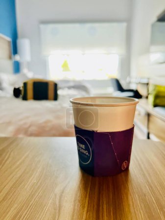 Photo for Interior of empty motel room with focus on paper disposable cup of morning coffee - Royalty Free Image