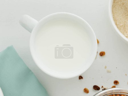 Top view of white cup of milk on white table