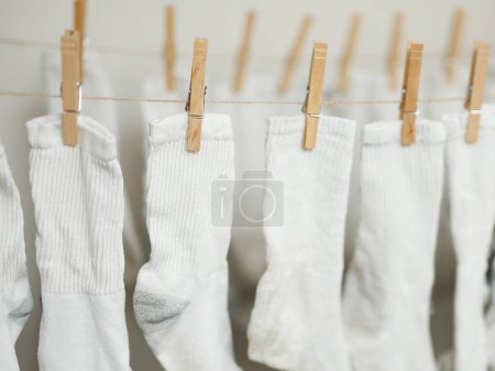 White socks clipped to rope to air dry indoors to save money on energy costs