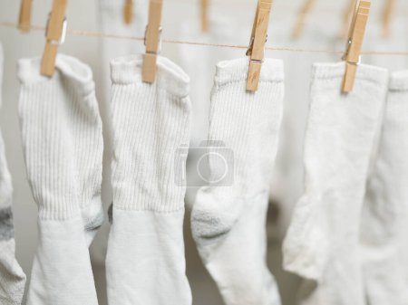 Weiße Socken, die an Seilen befestigt sind, um in Innenräumen trocknen zu können, um Energiekosten zu sparen