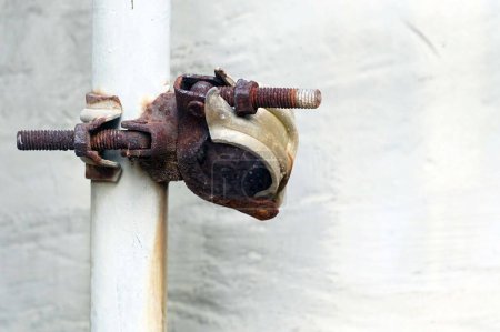 Téléchargez les photos : Un tuyau de serrage très rouille s'accroche à un vieux tuyau en PVC. - en image libre de droit