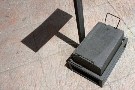 Téléchargez les photos : Une boîte en métal noir pour le poids avec ombre sur le sol d'un debout une étiquette annonces pour la texture et le fond. - en image libre de droit