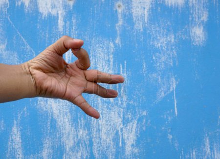 Téléchargez les photos : Main de l'homme au symbole signifie d'accord sur un bleu avec blanc peint sur un mur de ciment avec chemin de coupe, concept de signe abstrait. - en image libre de droit