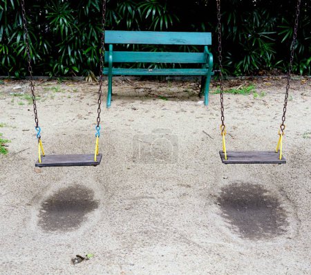 Téléchargez les photos : Une vieille balançoire dans l'aire de jeux sur le dos de sable ont la chaise verte dans le parc - en image libre de droit